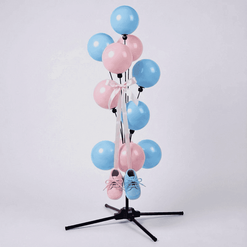 Sweet gender reveal balloon fountain with pink and blue baby booties hanging from golden ribbons between the balloons