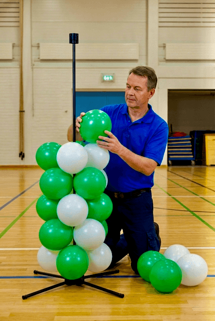 School staff member assembling PilaMania balloon decoration for graduation ceremony